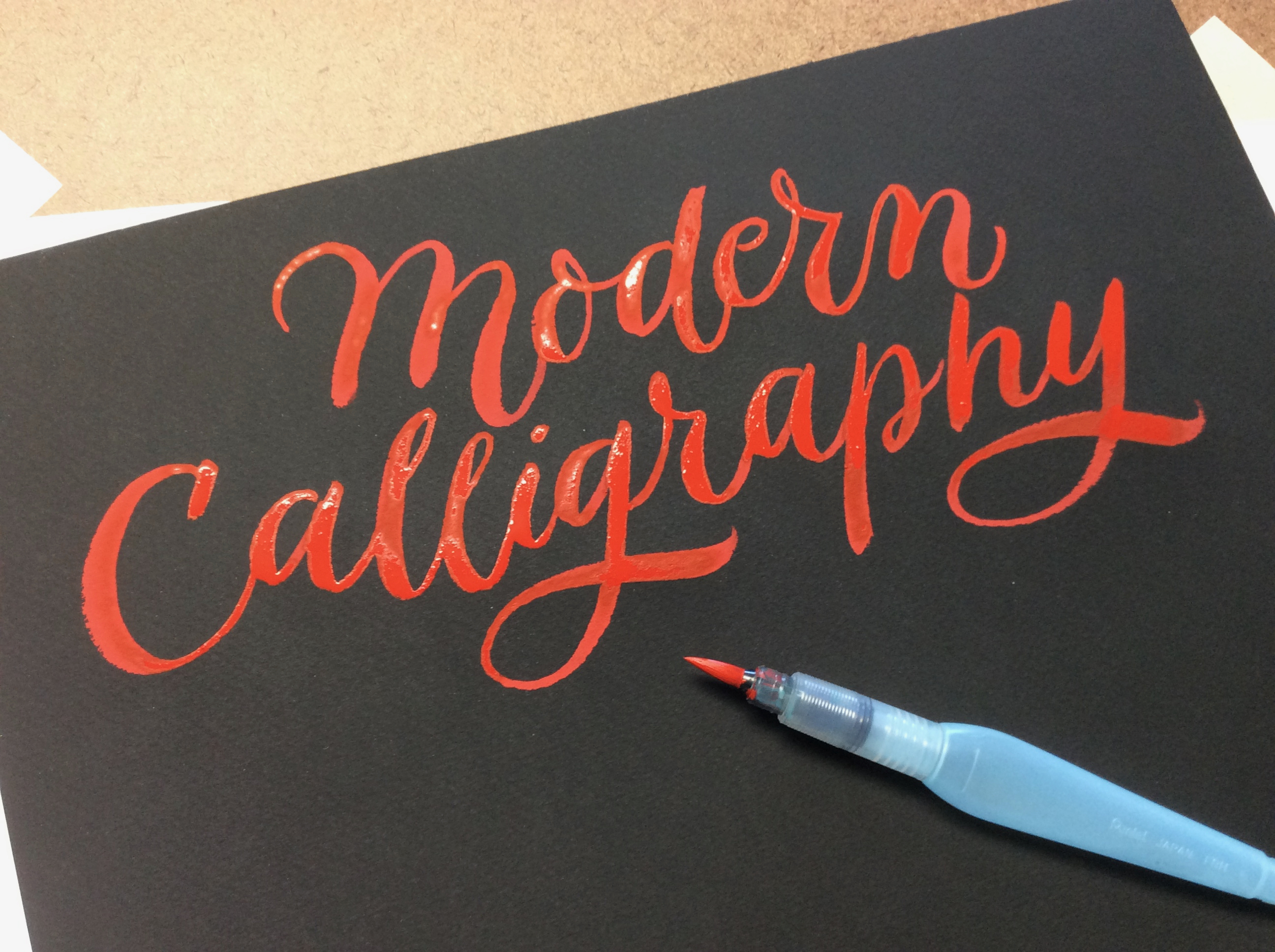 paper with text "modern calligraphy" and calligraphy brush