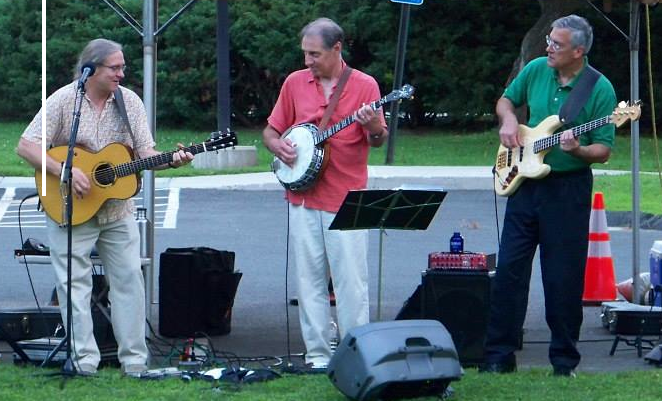 Three musicians outdoors with guitars and banjo