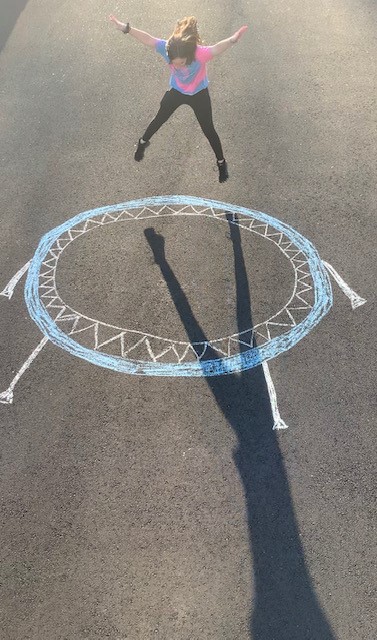 girl with shadow jumping on chalk drawing of trampoline