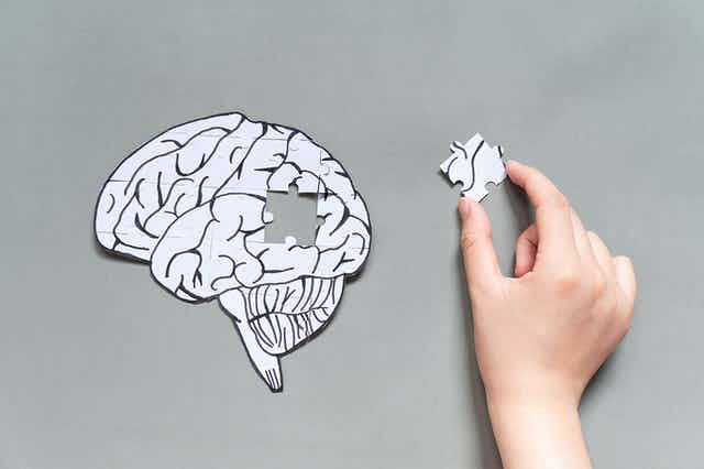 brain jigsaw puzzle and hand with puzzle piece