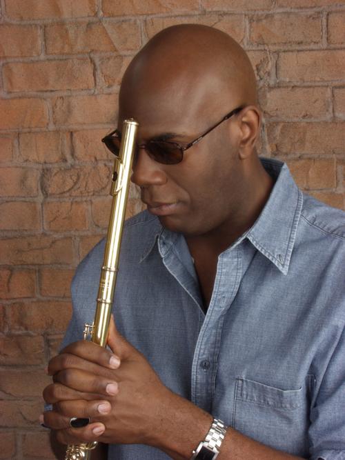 Flautist with his instrument against brick wall 