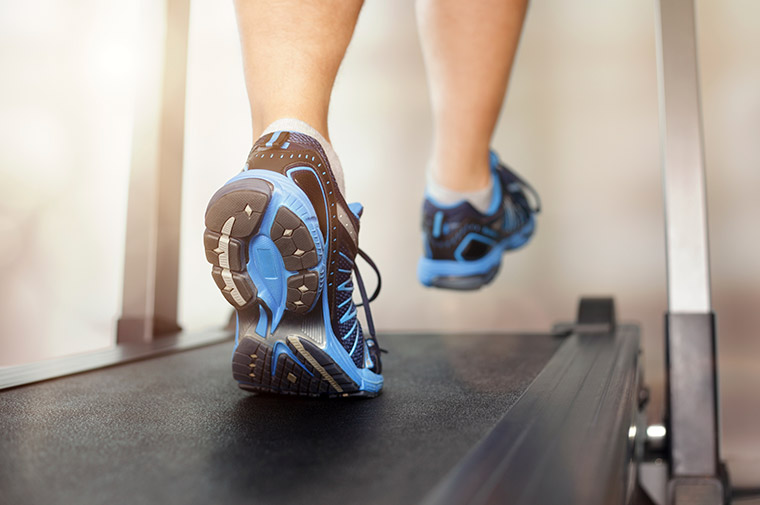Photo showing a treadmill and feet in sneakers.