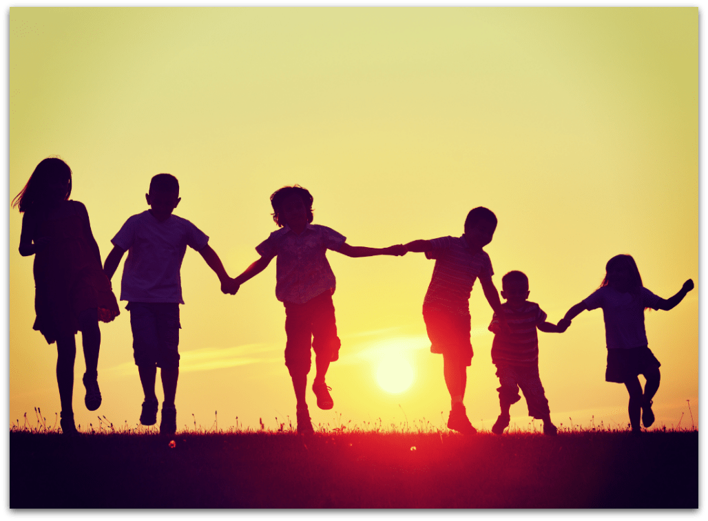Children holding hands at sunset
