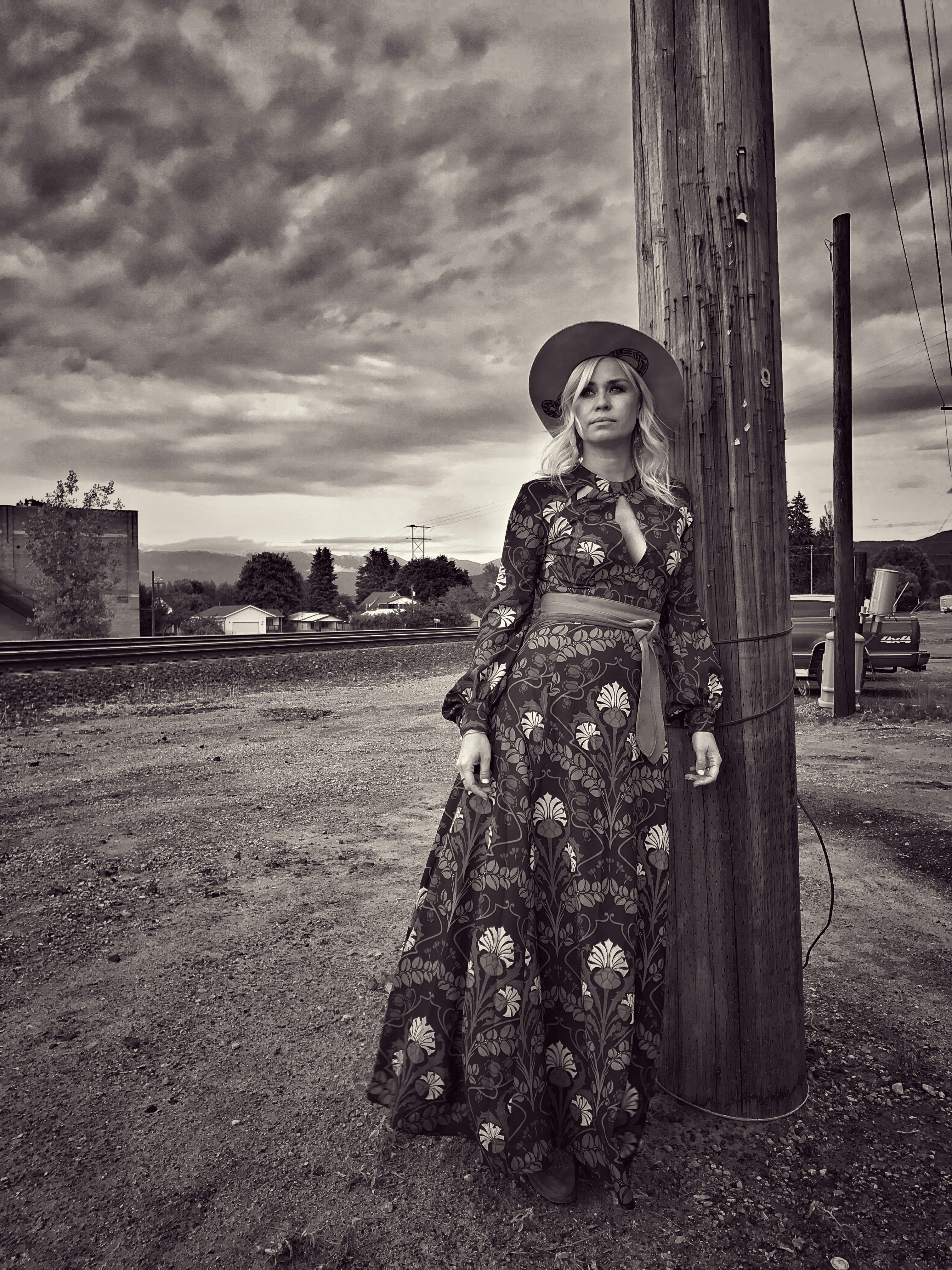 Black and white photograph of Sofia Talvik standing next to a telephone pole with a cloudy sky