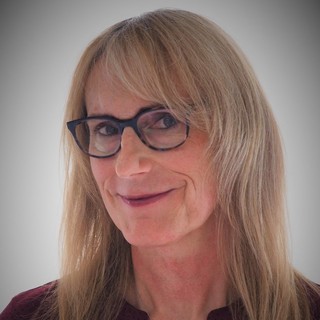 a person in glasses and medium length blond hair, head shot. 