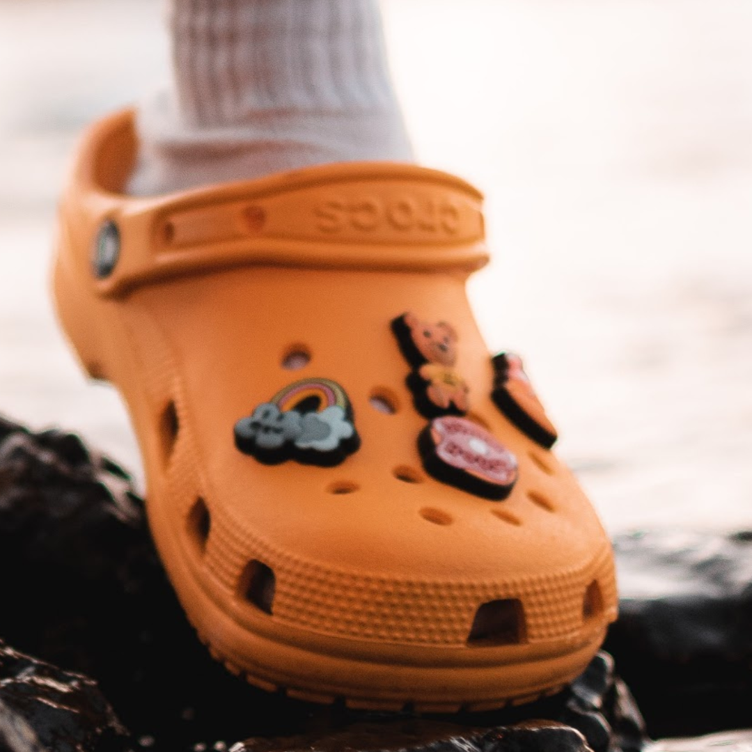 Photo of an orange croc with croc charms on it.