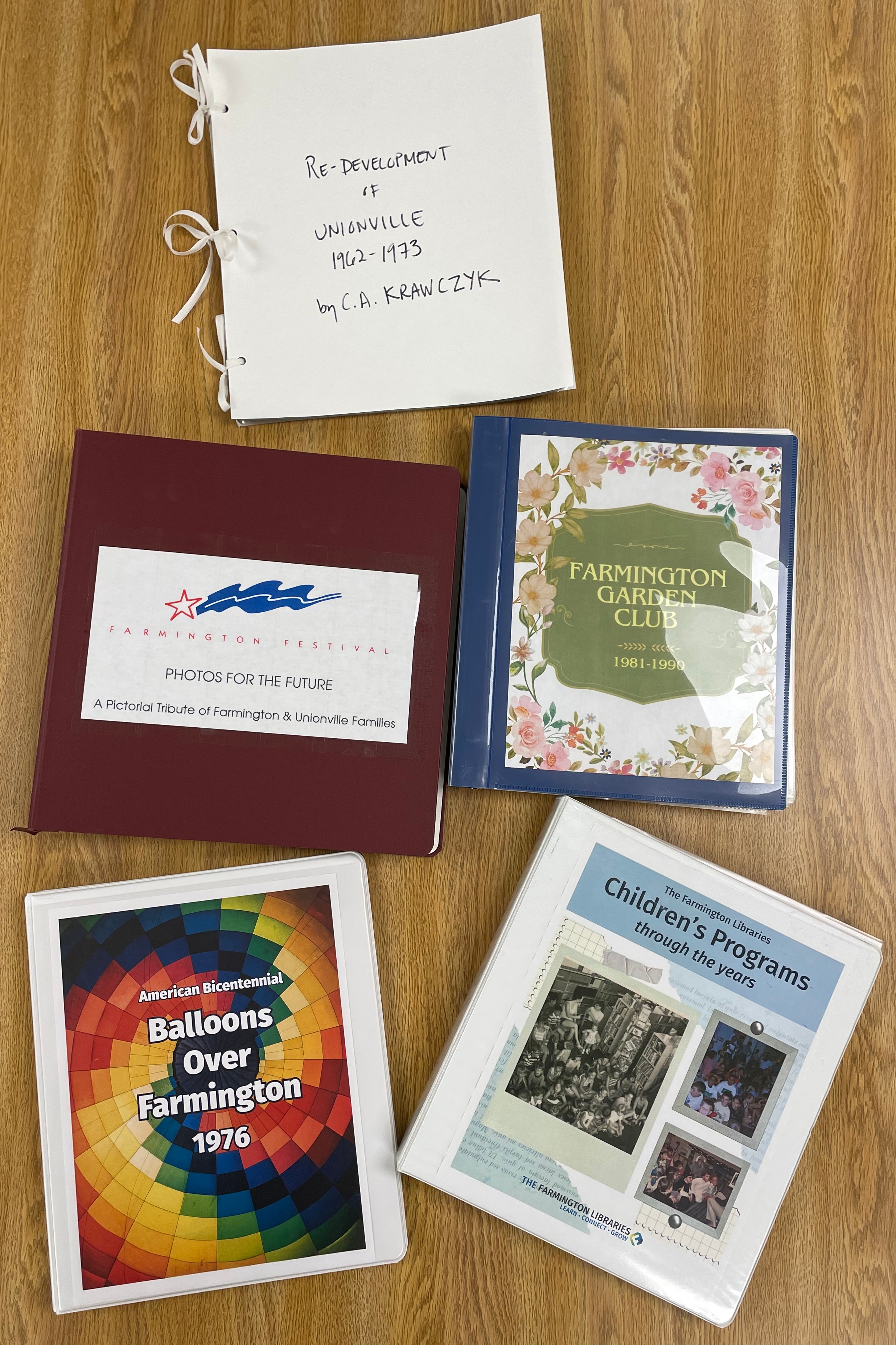 Five binders with brightly-colored covers on a table.