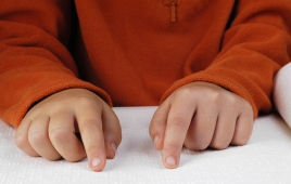 Child's hands reading braille