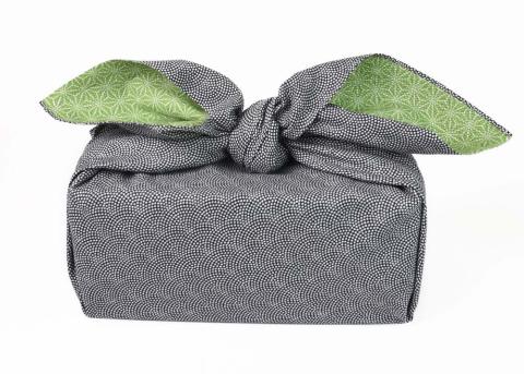 a box wrapped in a black patterned scarf that has lime green coloring on the reverse