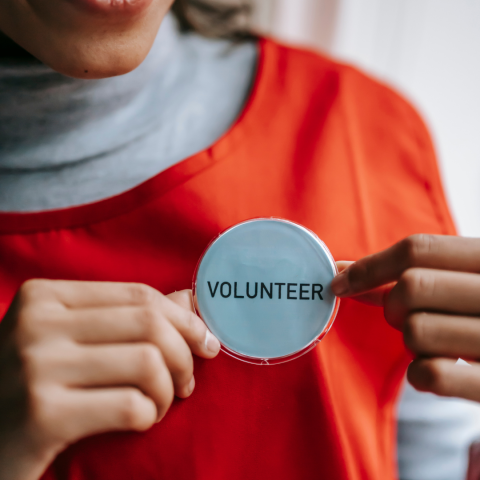 Person holding a button that says "volunteer" on it.