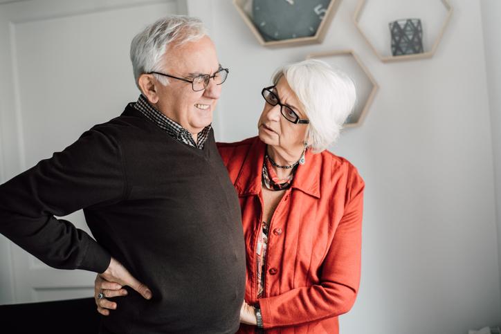 Man grimacing in pain while a woman looks concerned about him.
