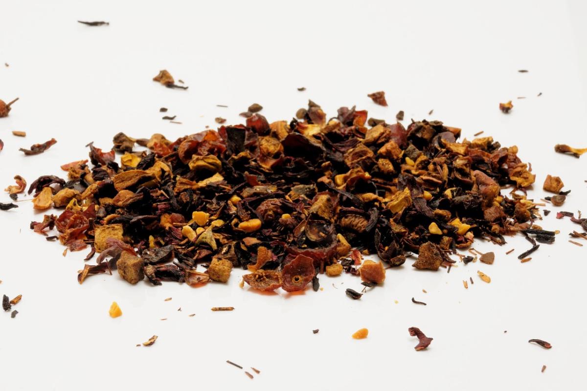 A pile of herbs and pieces of dried fruits on a white table. 