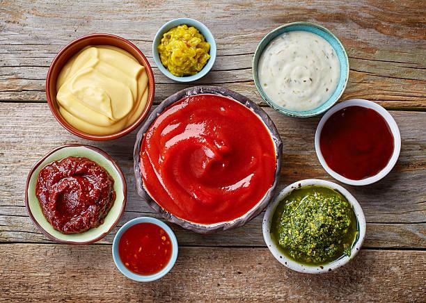 a photo of small bowls of condiments on a wooden background
